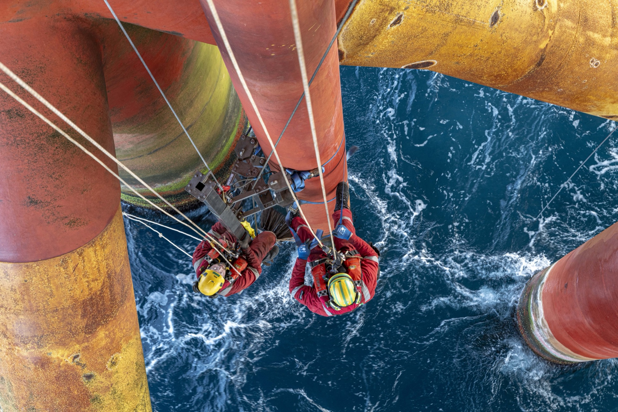 Rope access workers on offshore platform legs above the ocean